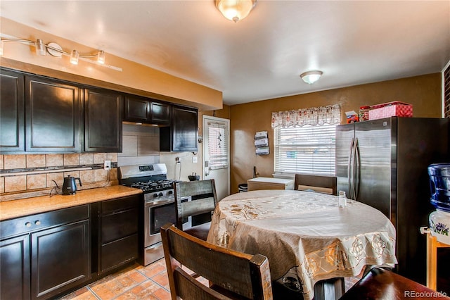 kitchen featuring light tile patterned flooring, dark brown cabinetry, appliances with stainless steel finishes, and tasteful backsplash