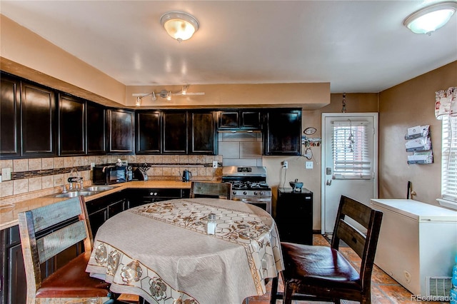 kitchen featuring refrigerator, backsplash, stainless steel range with gas cooktop, and sink