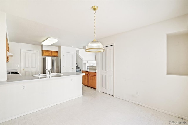 kitchen with hanging light fixtures, stainless steel fridge, and sink