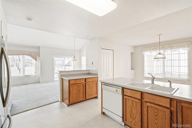 kitchen featuring stainless steel refrigerator, decorative light fixtures, sink, white dishwasher, and a textured ceiling