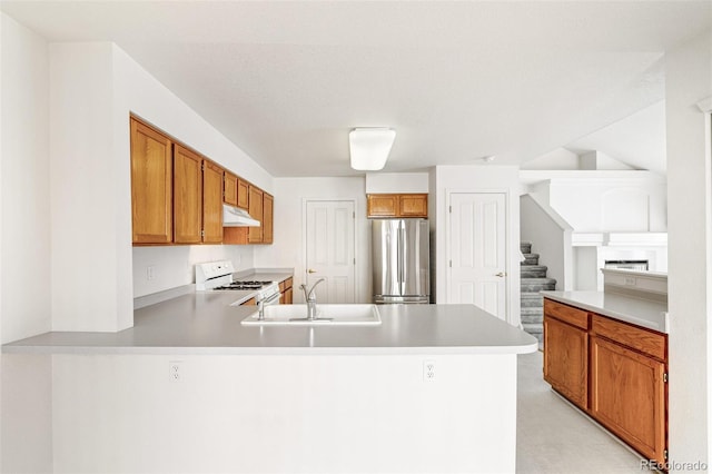 kitchen with sink, white gas stove, stainless steel fridge, and kitchen peninsula