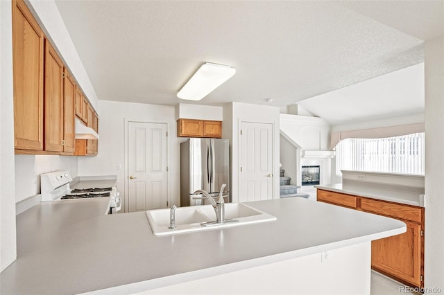 kitchen with sink, stainless steel fridge, white gas range oven, a textured ceiling, and kitchen peninsula