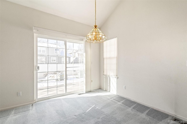 spare room featuring an inviting chandelier, lofted ceiling, and carpet flooring