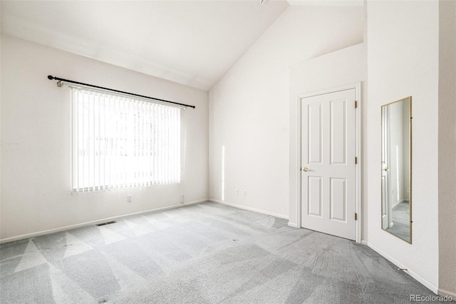 carpeted empty room featuring high vaulted ceiling