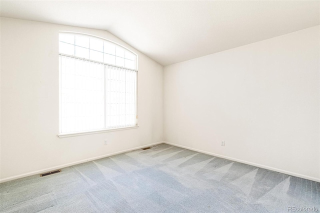 carpeted empty room with lofted ceiling