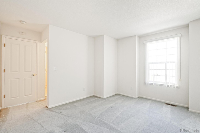 spare room with light carpet and a textured ceiling