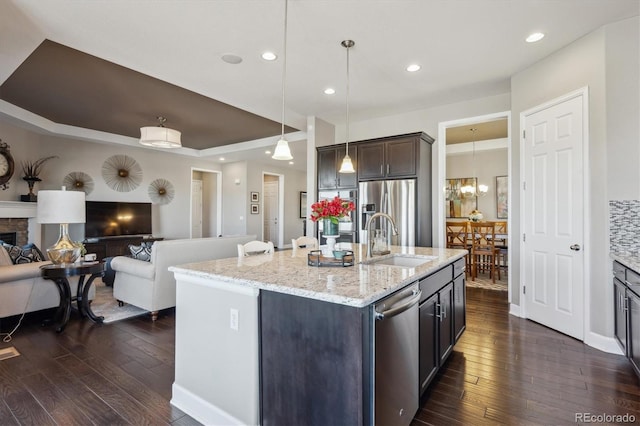 kitchen featuring dark wood finished floors, a sink, dark brown cabinetry, appliances with stainless steel finishes, and open floor plan