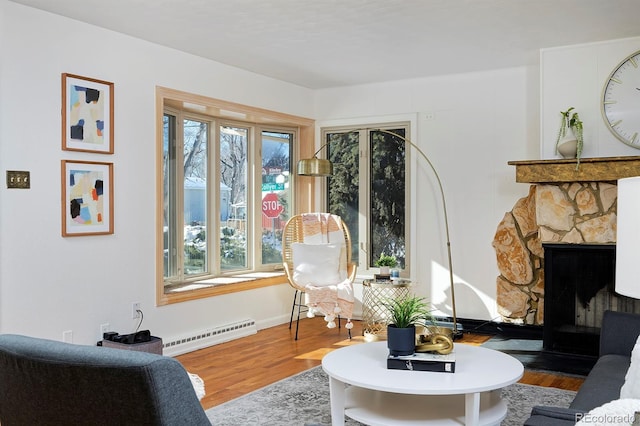 living area featuring hardwood / wood-style flooring, a baseboard radiator, and a fireplace