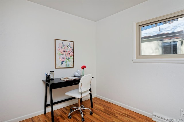 office space featuring a baseboard heating unit and hardwood / wood-style floors