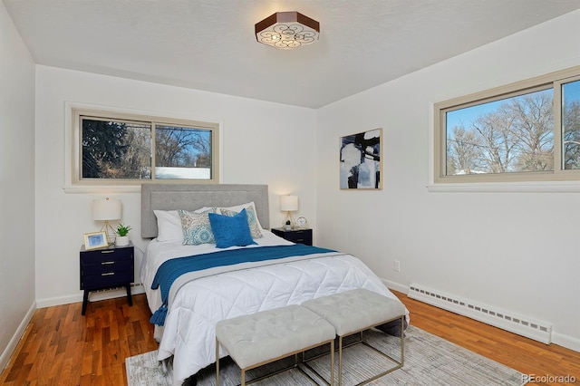 bedroom with a baseboard heating unit and dark hardwood / wood-style floors