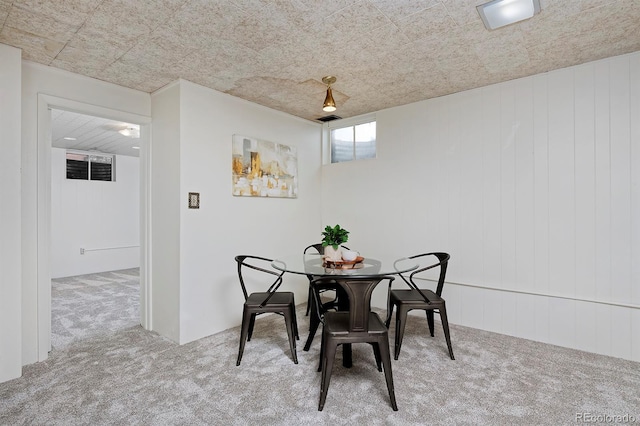 dining room featuring light colored carpet and wood walls