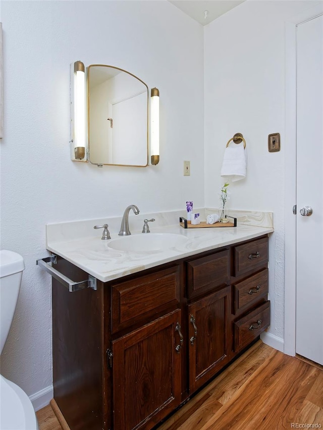 bathroom with vanity, toilet, and hardwood / wood-style floors