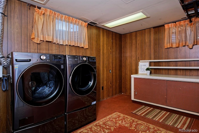 clothes washing area featuring independent washer and dryer and wooden walls