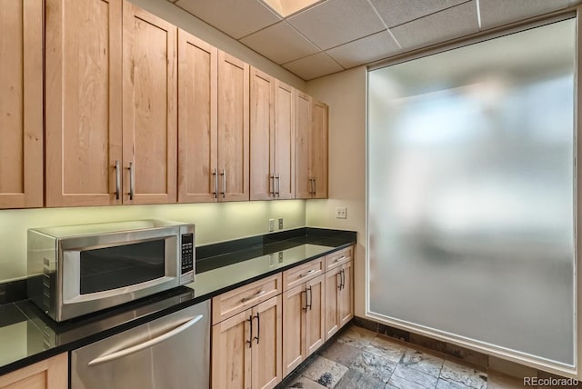 1499 Blake St Unit 1A & 1B, Denver, CO 80202 - kitchen with stainless steel appliances, light brown cabinetry, dark countertops, dark stone finish floors, and baseboards