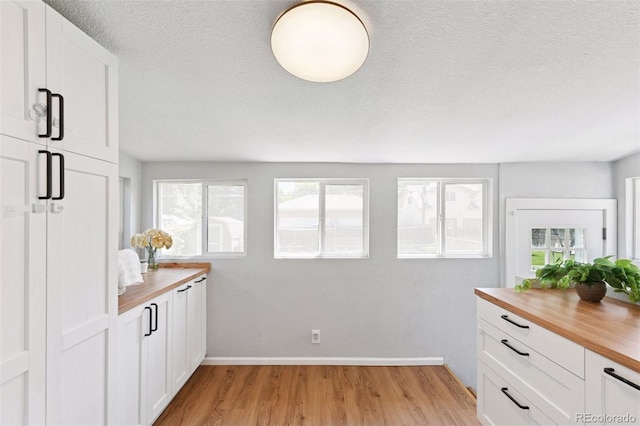 3976 S Washington St, Englewood, CO 80113 - kitchen with butcher block countertops, light wood finished floors, white cabinetry, and a textured ceiling