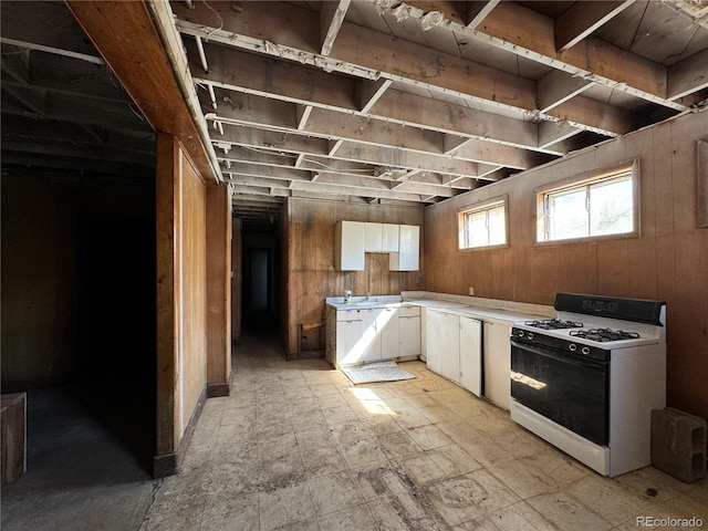 kitchen with light tile patterned flooring, wood walls, white cabinets, and white range with gas stovetop