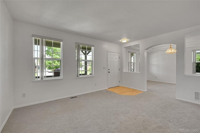6910 E 131st Dr, Thornton, CO 80602 - foyer featuring light carpet, plenty of natural light, arched walkways, and a chandelier