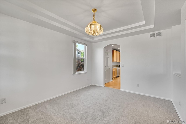 6910 E 131st Dr, Thornton, CO 80602 - empty room with arched walkways, light colored carpet, a raised ceiling, and a chandelier
