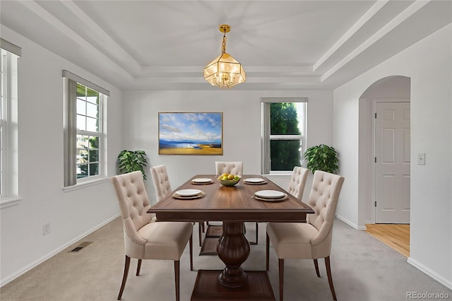 6910 E 131st Dr, Thornton, CO 80602 - dining area with light colored carpet, a tray ceiling, arched walkways, and a chandelier