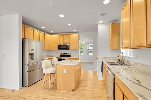 6910 E 131st Dr, Thornton, CO 80602 - kitchen with stainless steel appliances, a kitchen island, light wood-style flooring, recessed lighting, and arched walkways