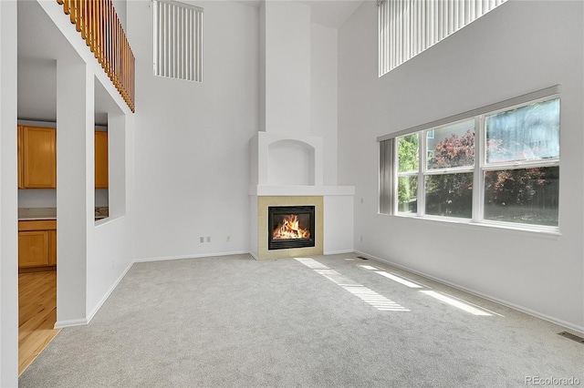 6910 E 131st Dr, Thornton, CO 80602 - unfurnished living room featuring light colored carpet, a high ceiling, and a tile fireplace