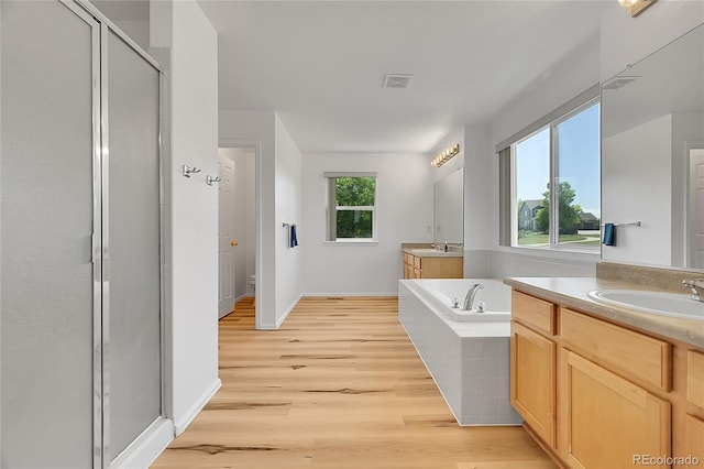 6910 E 131st Dr, Thornton, CO 80602 - bathroom featuring a shower stall, two vanities, wood finished floors, and a garden tub