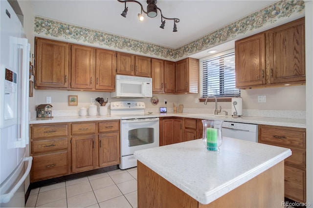 kitchen featuring a center island, sink, light tile patterned floors, and white appliances