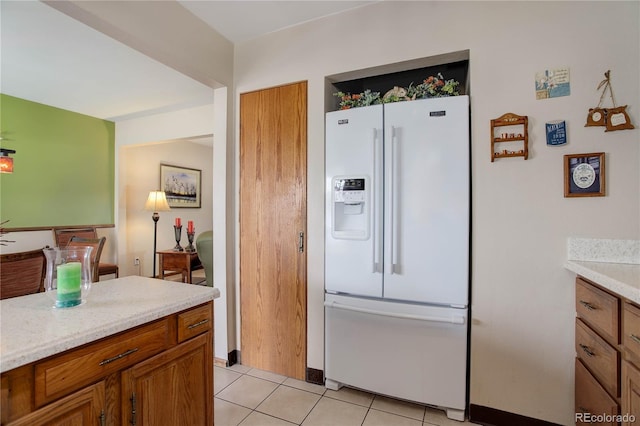 kitchen with white refrigerator with ice dispenser and light tile patterned floors