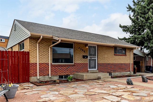 ranch-style house with brick siding, central air condition unit, roof with shingles, and fence
