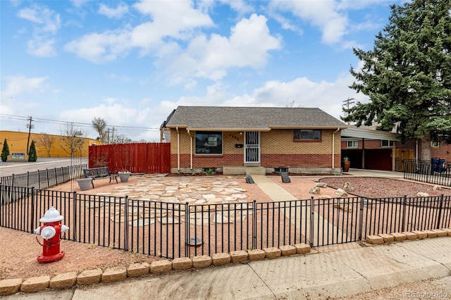 view of front facade with brick siding, a shingled roof, a carport, and a fenced front yard