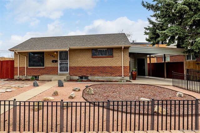 single story home featuring brick siding, roof with shingles, and a fenced front yard