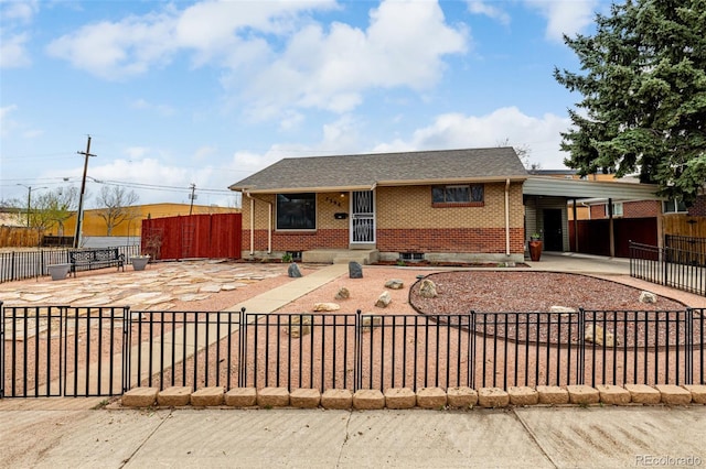 ranch-style home featuring concrete driveway, brick siding, a carport, and a fenced front yard