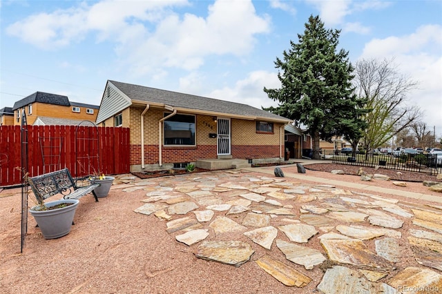 rear view of property with fence, brick siding, and a patio