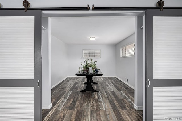 hallway with baseboards, dark wood-style flooring, and a barn door