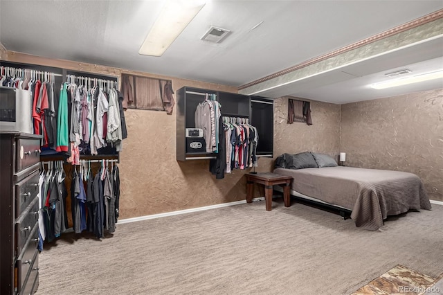 bedroom with a textured wall, visible vents, and carpet