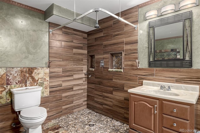 full bath featuring a tile shower, toilet, vanity, and tile walls