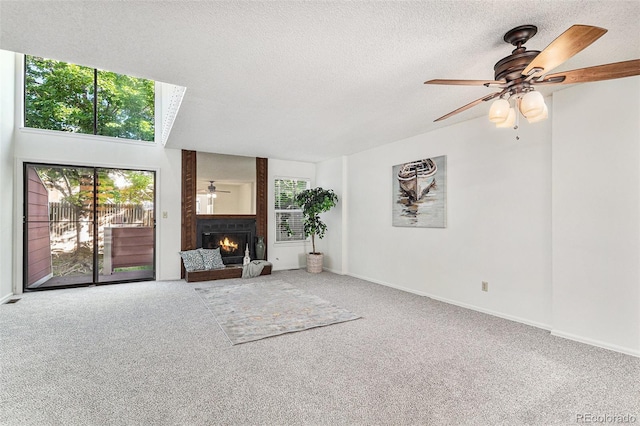 480 W Rockrimmon Blvd Unit D, Colorado Springs, CO 80919 - unfurnished living room with plenty of natural light, a warm lit fireplace, carpet floors, and a textured ceiling