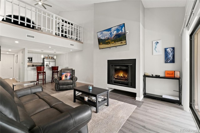 1160 S Monaco Pkwy Unit 6, Denver, CO 80224 - living room with high vaulted ceiling, a warm lit fireplace, ceiling fan, and light wood finished floors
