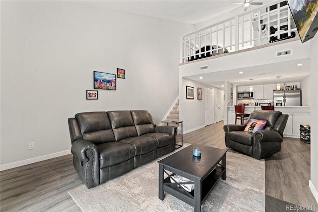 1160 S Monaco Pkwy Unit 6, Denver, CO 80224 - living room with stairs, light wood finished floors, ceiling fan, a towering ceiling, and recessed lighting