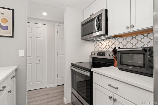 1160 S Monaco Pkwy Unit 6, Denver, CO 80224 - kitchen with stainless steel appliances, light wood-style floors, white cabinets, backsplash, and recessed lighting