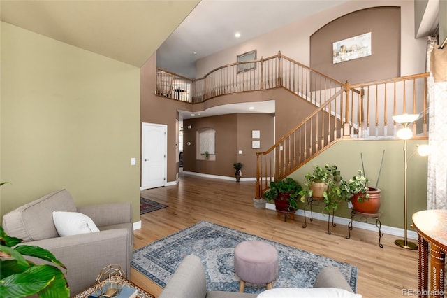 living room with a towering ceiling, wood finished floors, baseboards, and stairs