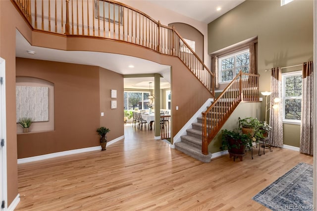 entrance foyer featuring a high ceiling, wood finished floors, baseboards, and plenty of natural light