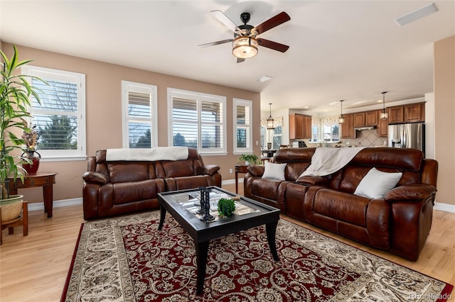 living area with ceiling fan, light wood-type flooring, and baseboards