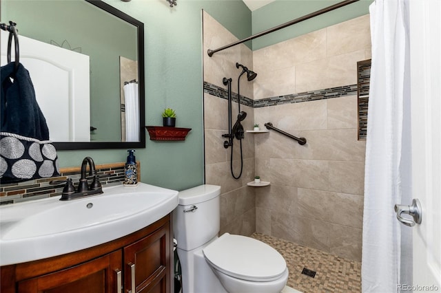 bathroom with a tile shower, tasteful backsplash, vanity, and toilet