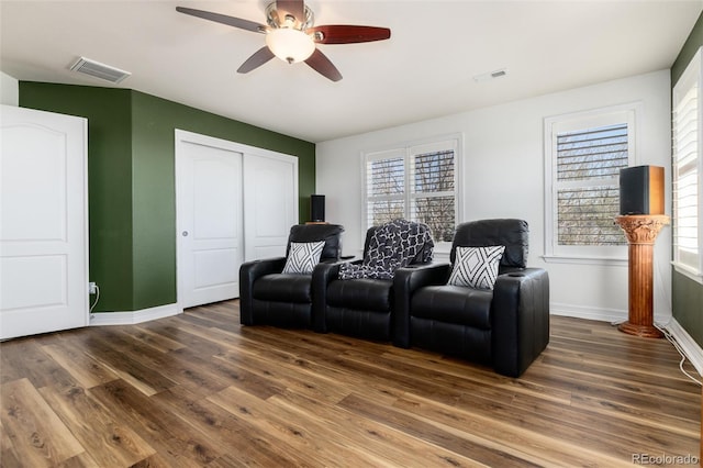 cinema room featuring wood finished floors, baseboards, a ceiling fan, and visible vents
