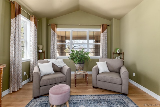 living area featuring wood finished floors, baseboards, and lofted ceiling