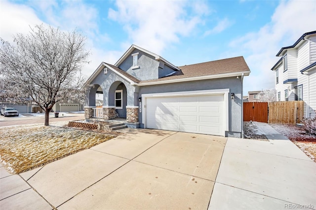 traditional home featuring concrete driveway, stone siding, an attached garage, fence, and stucco siding