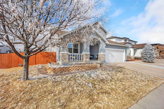 view of front of house with an attached garage, fence, driveway, stone siding, and stucco siding