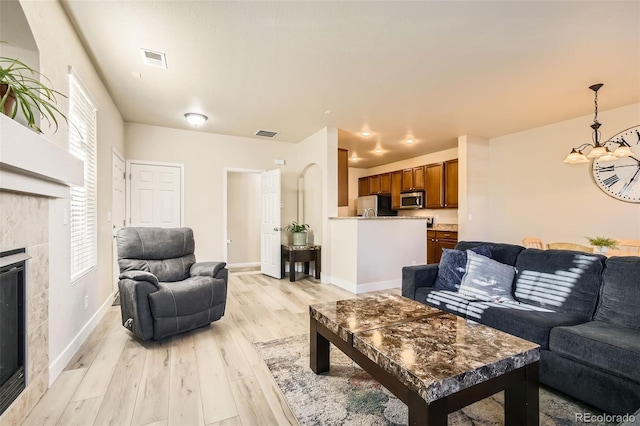 living room featuring a tiled fireplace and light hardwood / wood-style flooring