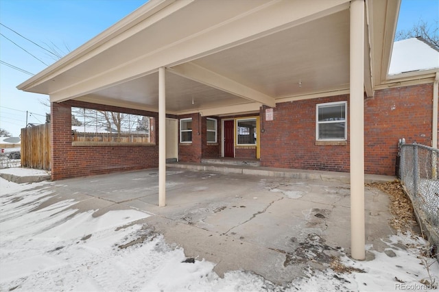 snow covered patio with fence and an attached carport